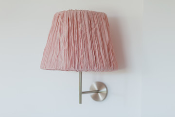 Wall pink shade lamp over the bed on a white wall
