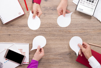 team is meeting at desk and extending speech bubbles