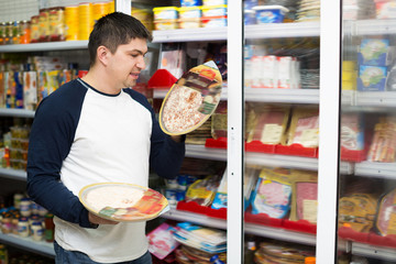 Man looking at assortment of frozen pizza
