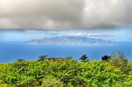 Island of brave at sea in between the clouds and trees as seen from sister island of Fogo in Cabo Verde