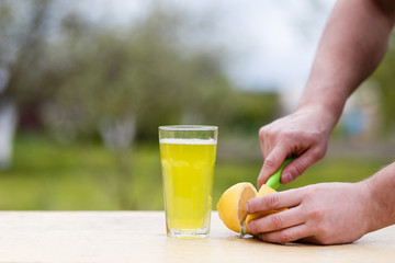 Energy drink into a glass on a wooden table. lemon cut with a knife shed. Side view of homemade lemonade cooking with yellow lemon and water in glass jar in wooden table.