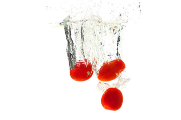 Tomatoes falling in the water with splash, isolated on a white background