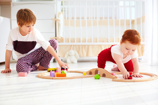 cute kids, brothers playing together with wooden toy railway in nursery room