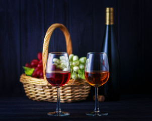 Glass of red and white wine with a de-focused bottle and fruits on back