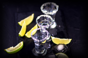 Set of tequila shots on a dark wooden background with de-focused back