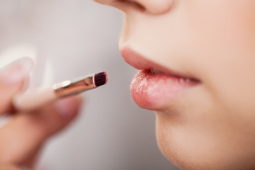 Backstage scene: Professional Make-up artist doing makeup for young businesswoman at beauty salon. Close up