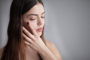 Fototapeta premium Beautiful Young Woman with Clean Fresh Skin touch own face . Facial treatment . Cosmetology , beauty and spa