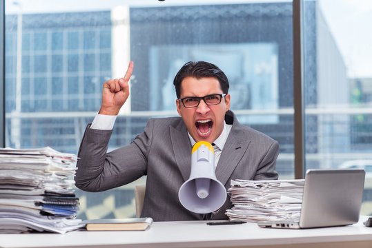 Angry businessman with loudspeaker in the office