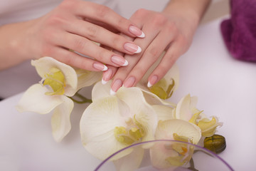 Nail Salon. Closeup Of Beautician Hands Cleaning Female Client's Nails With Orange Wooden Stick, Cuticle Pusher, Removing Cuticles In Beauty Salon. Woman Hands Nail Care And Manicure. High Resolution