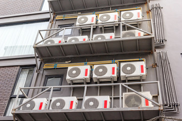 Group of compressors of air conditioner hanging on the grey wall.
