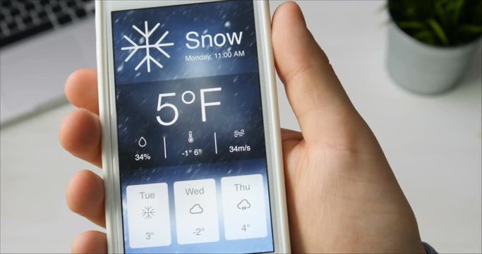 Checking wather using smartphone app. Snowy and cold