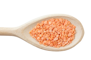 Red lentils on wooden spoon isolated on white.