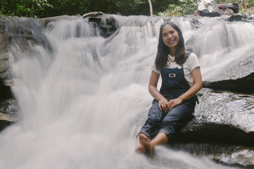 Beautiful young traveling woman enjoy the waterfall.vintage tone hipster style and soft focus.