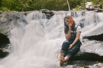 Beautiful young traveling woman enjoy the waterfall.vintage tone hipster style and soft focus.