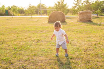 Happy laughing baby boy playing on summer or autumn field.