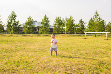 Naklejka na ściany i meble smiling boy in the field at sunny summer morning. boy in white shirt. The family travels, child happily ran around the field