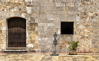 The facade of the wall of the old building, with a stand under the torch and a potted plant