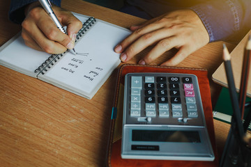 hand Asian man calculate finances and accounting for monthly expenses / charges or cost on notebook...