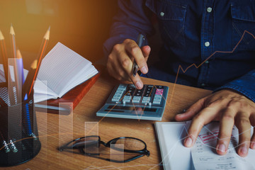 Asian man accountant or banker calculate finances / savings money or economy concept.Idea for save coin and accounting. Essential accessories on table office desk.Sun flare light.
