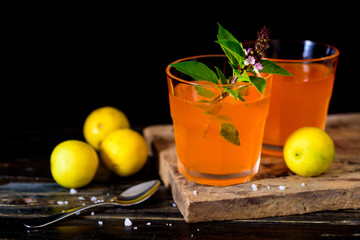 Orange cocktail in crystal glass decorated with sweet basil on a wooden plate with lemon yellow to prepare drinks for the party.