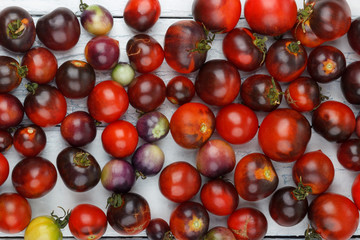 Different tomatoes on the white wooden background