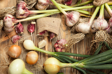 Fresh vegetables, garlic and onions on a rustic wooden background. View from above.