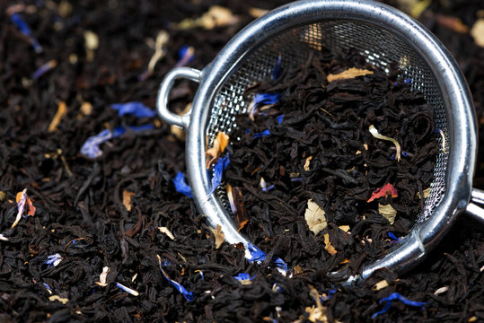 dry black tea with aromatic herbs in a strainer, closeup
