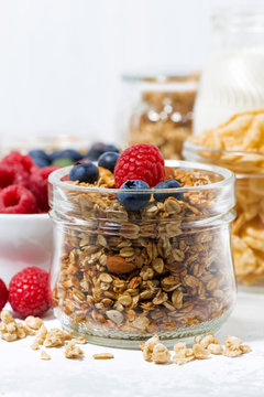 healthy products for breakfast, granola and berries on white table, vertical closeup