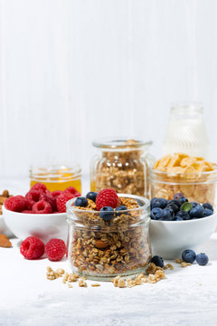 healthy products for breakfast, granola and berries on white table, vertical