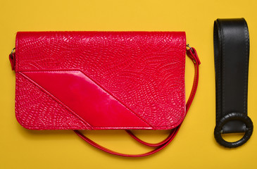 Retro style red leather bag and belt from 80s on a bright yellow background. Top view.