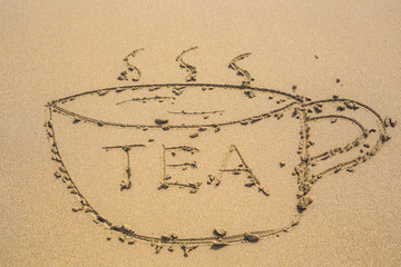 cup of tea drawn on sand and word tea written on a beach