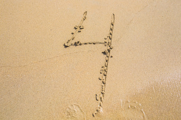 The number four drawn on sand at the beach, holiday concept background