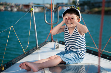 happy kid captain sitting on luxury boat with sea background behind