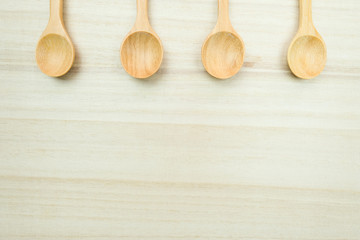 Handcrafted wooden spoons lying on a wood surface with copyspace