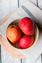 Fresh organic pears in wooden bowl on board on wooden table background. Healthy vegetarian food content. Top view