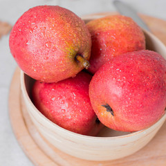 Fresh organic pears in wooden bowl on board on wooden table background. Healthy vegetarian food content. Close up, top view
