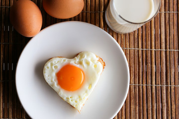 Fried egg in heart shape and milk