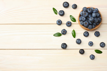blueberries in wooden bowl on light wooden table background. top view with copy space
