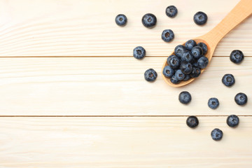 blueberries in wooden spoon on light wooden table background. top view with copy space