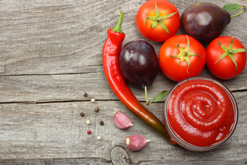raw plum, tomato, chili pepper and ketchup on wooden table. top view  with copy space