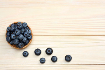 blueberries in wooden bowl on light wooden table background. top view with copy space