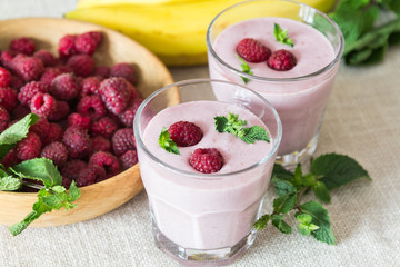 Two glasses of smoothies from banana and raspberries on a background of fruit - 166949429