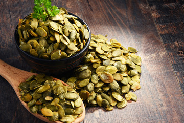 Composition with bowl of pumpkin seeds on wooden table