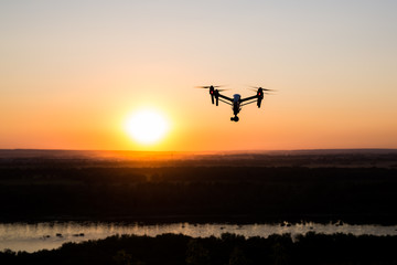 Fototapeta na wymiar quadrocopter drone with remote control. Dark silhouette against colorfull sunset.