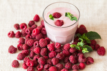 Glass smoothies made of banana and raspberries on a background of raspberries