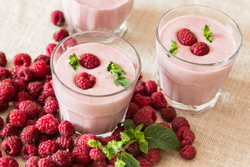 Two glasses of smoothies from banana and raspberries on a background of fruit