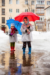 Portrait of little girls in boots and umbrellas