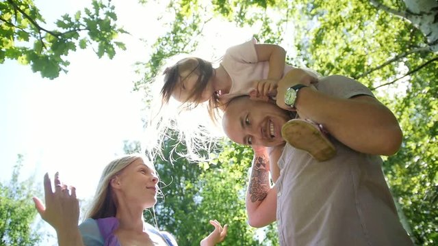 Father, mother and daughter having fun in park at sunny day, slow-motion