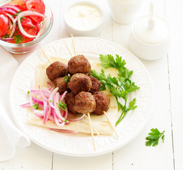 Lamb kebabs on skewers with onion and buttermilk sauce.