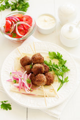 Lamb kebabs on skewers with onion and buttermilk sauce.